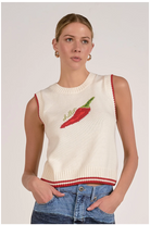 Woman wearing a white sleeveless sweater with a red chili pepper design on a plain background