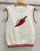 White knit sleeveless sweater with red chili pepper design and 'chillin' text on a wooden hanger.