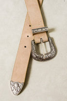Beige leather belt with silver embossed buckle on a light beige background