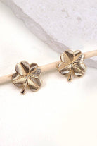 Gold four-leaf clover earrings on a light background