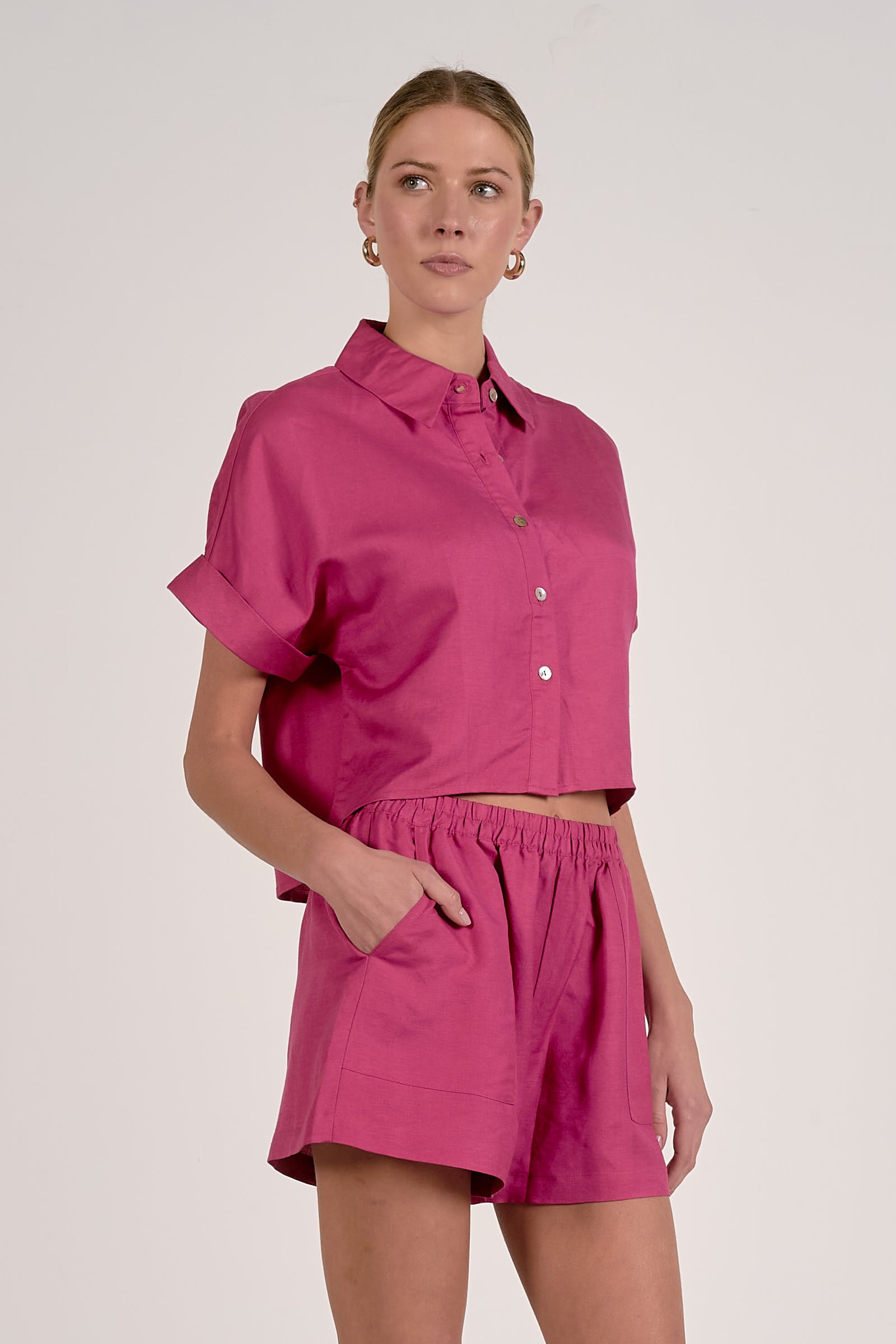 Woman wearing a pink outfit with a matching shirt and shorts on a white background