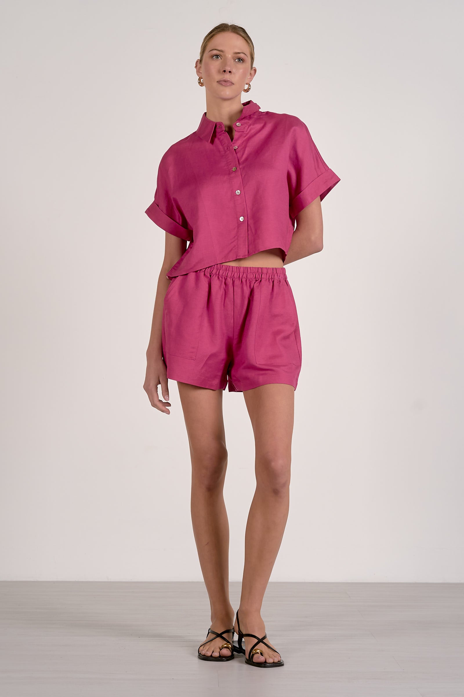 Woman wearing a pink outfit with a shirt and shorts on a white background