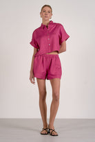 Woman wearing a pink outfit with a shirt and shorts on a white background