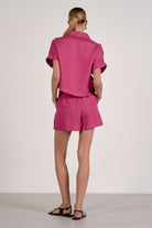 Person wearing a pink outfit with a matching shirt and shorts on a white background