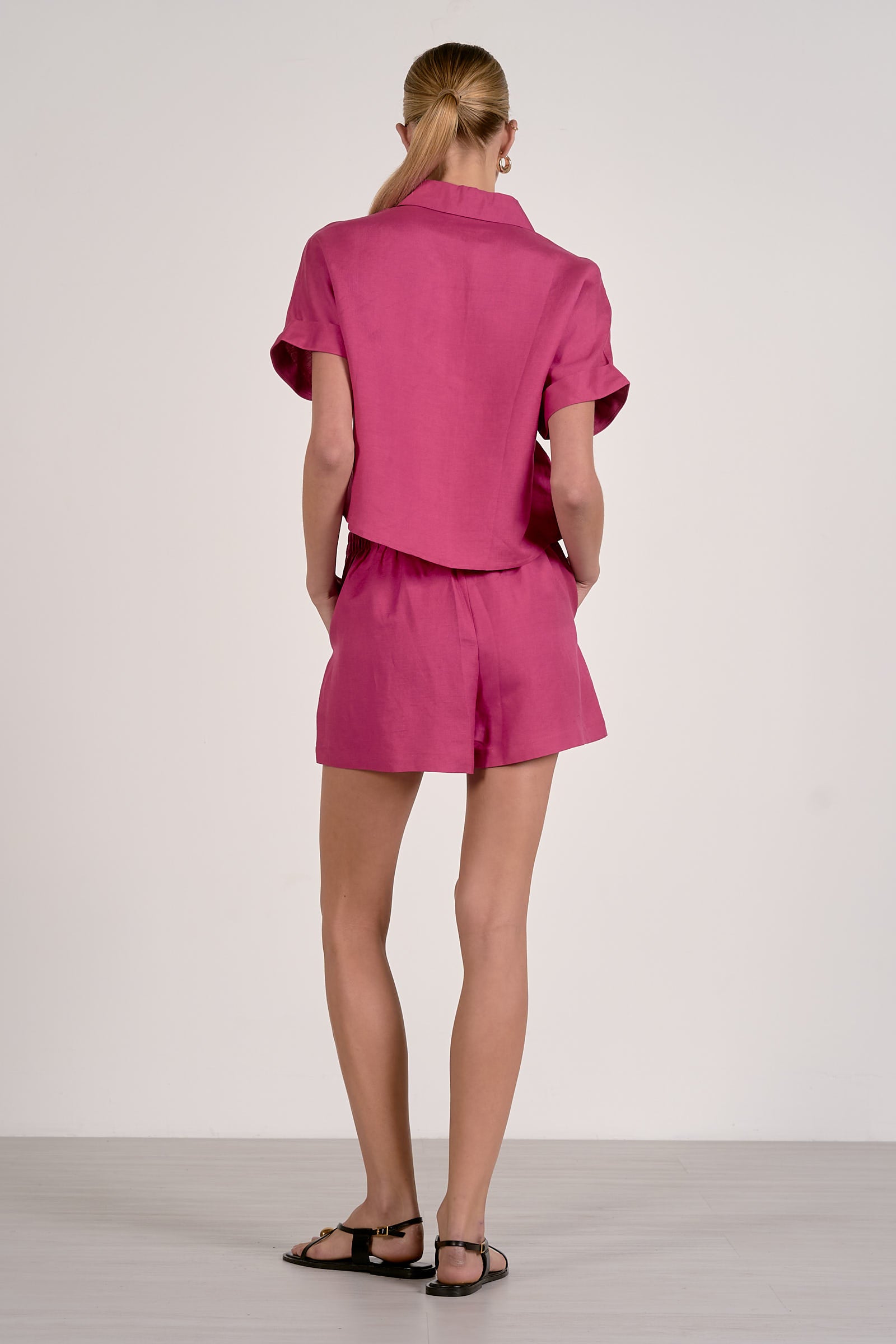 Person wearing a pink outfit with a matching shirt and shorts on a white background