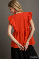 Woman wearing a tomato red top with ruffled sleeves against a gray background