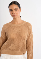 Woman wearing a beige knitted sweater against a white background