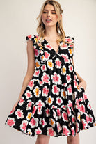 Woman wearing a black floral dress on a plain background
