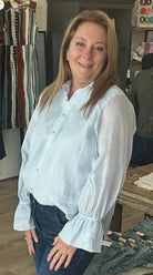 Woman wearing a light blue blouse in a clothing store setting