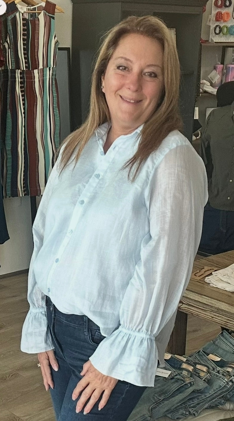 Woman wearing a light blue blouse in a clothing store setting