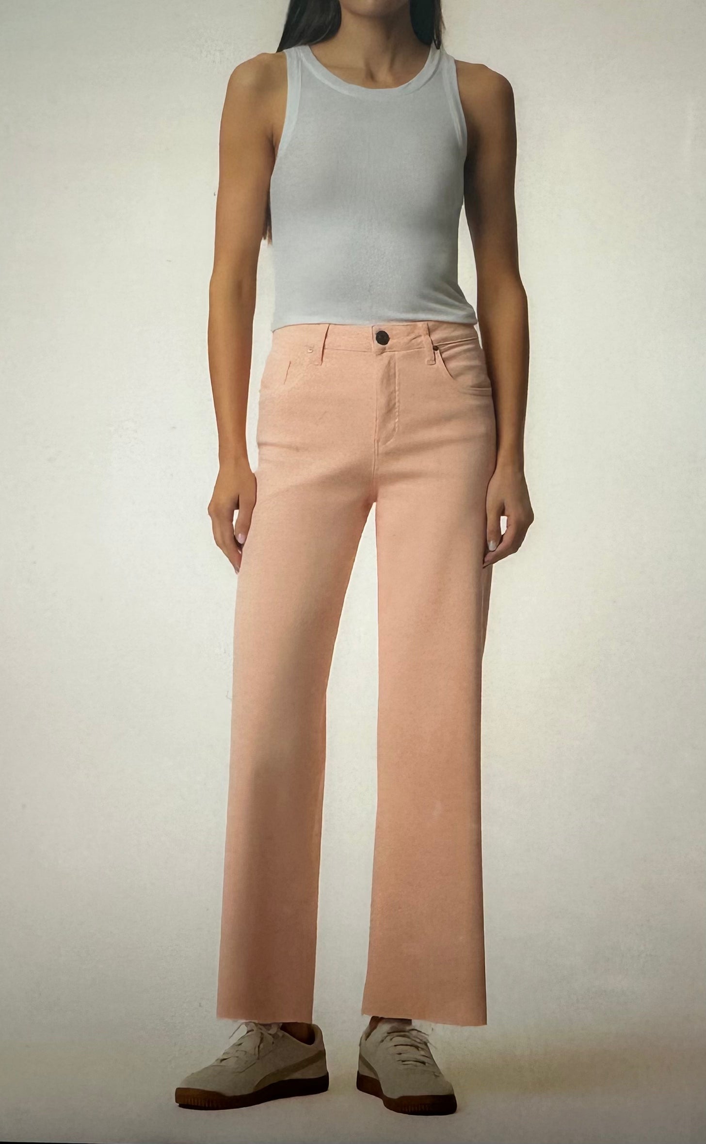 Person wearing a light gray tank top and pink pants on a plain background