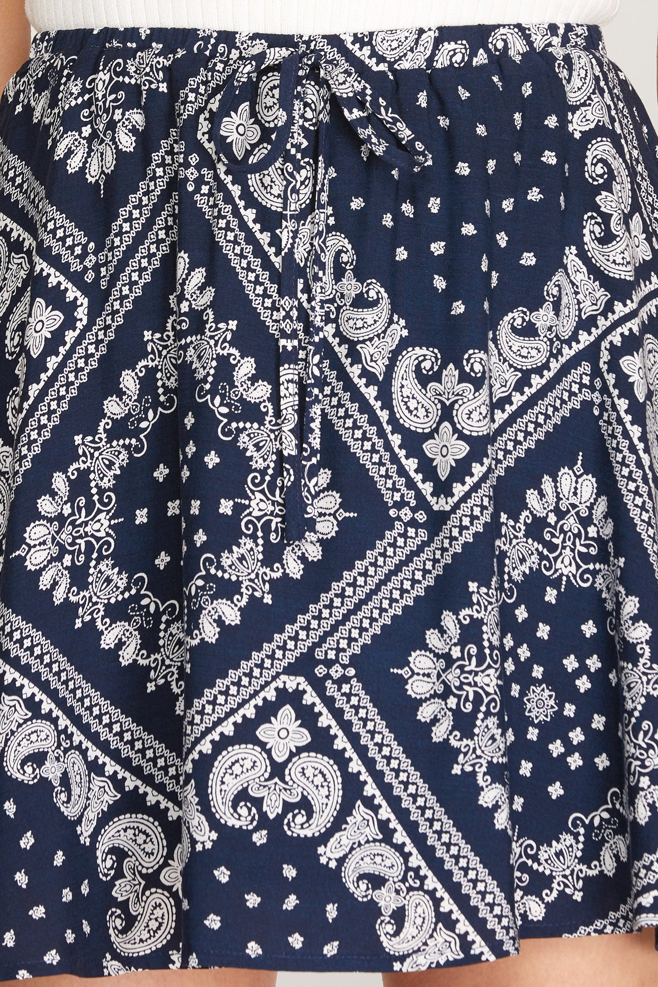 A close-up of a navy blue and white bandana print skirt with an elastic waist and tie, shown on a model.