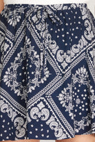 A close-up of a navy blue and white bandana print skirt with an elastic waist and tie, shown on a model.