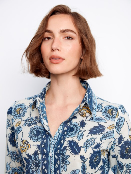 Woman wearing a blue floral patterned shirt against a white background