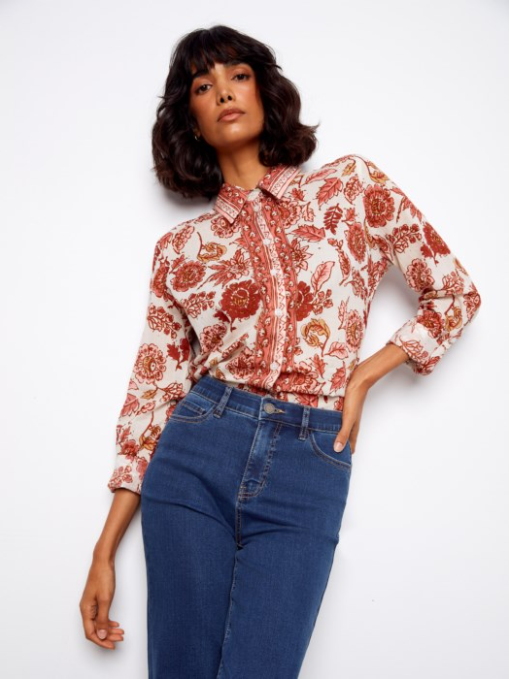 Woman wearing a floral blouse and blue jeans against a white background