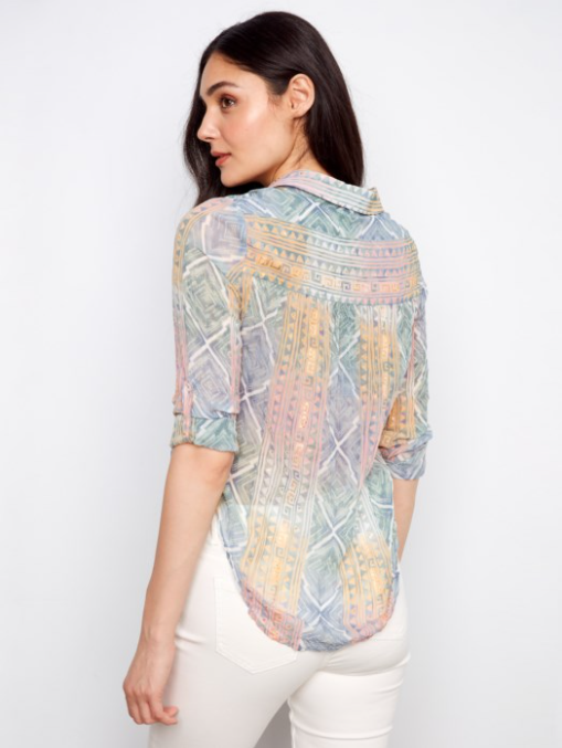 Woman wearing a patterned shirt with rolled-up sleeves on a white background