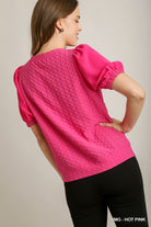 Woman wearing a hot pink textured top against a neutral background