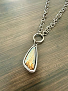 Necklace with a teardrop-shaped pendant on a wooden surface