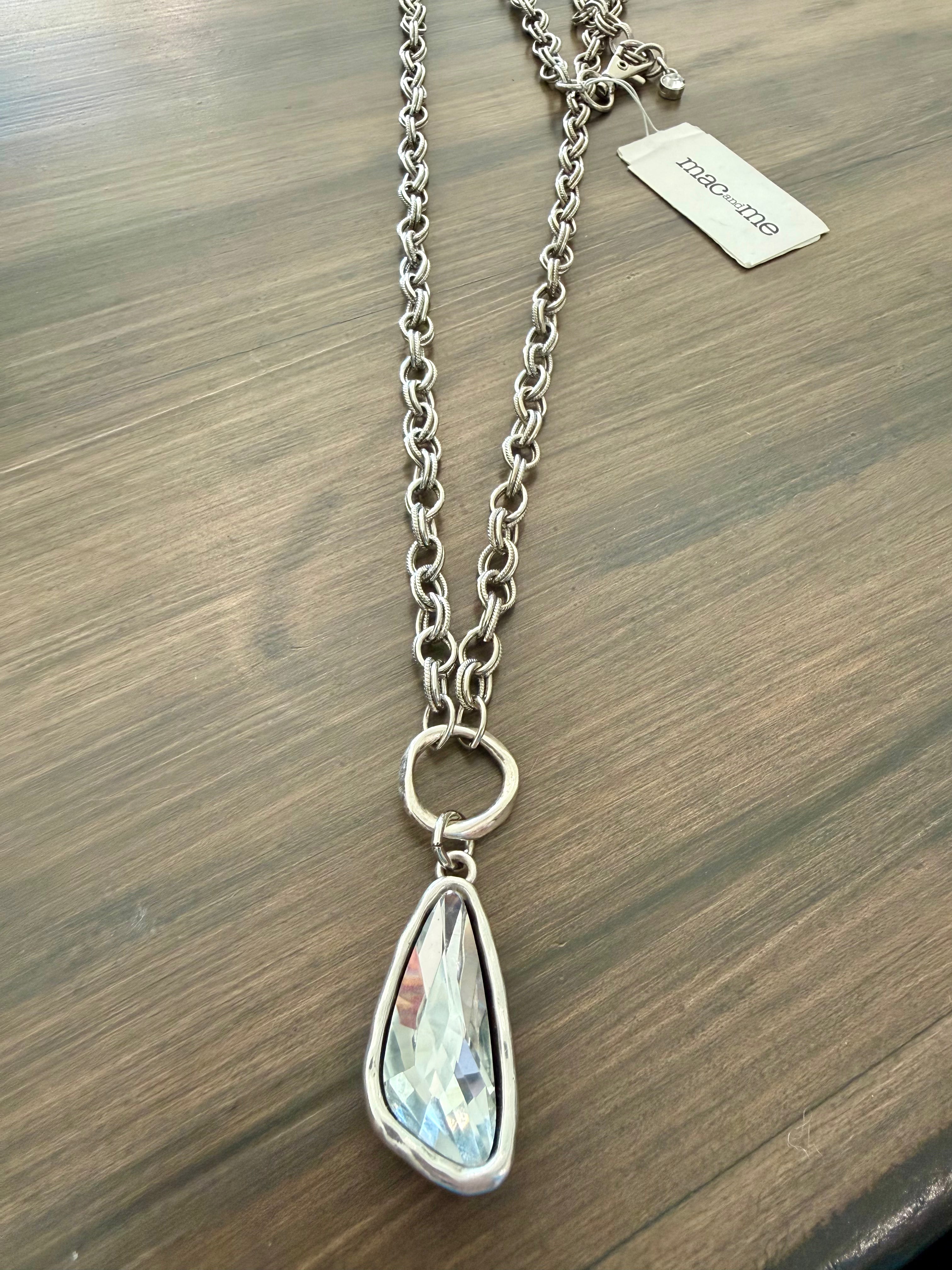 Silver necklace with a teardrop-shaped pendant on a wooden surface
