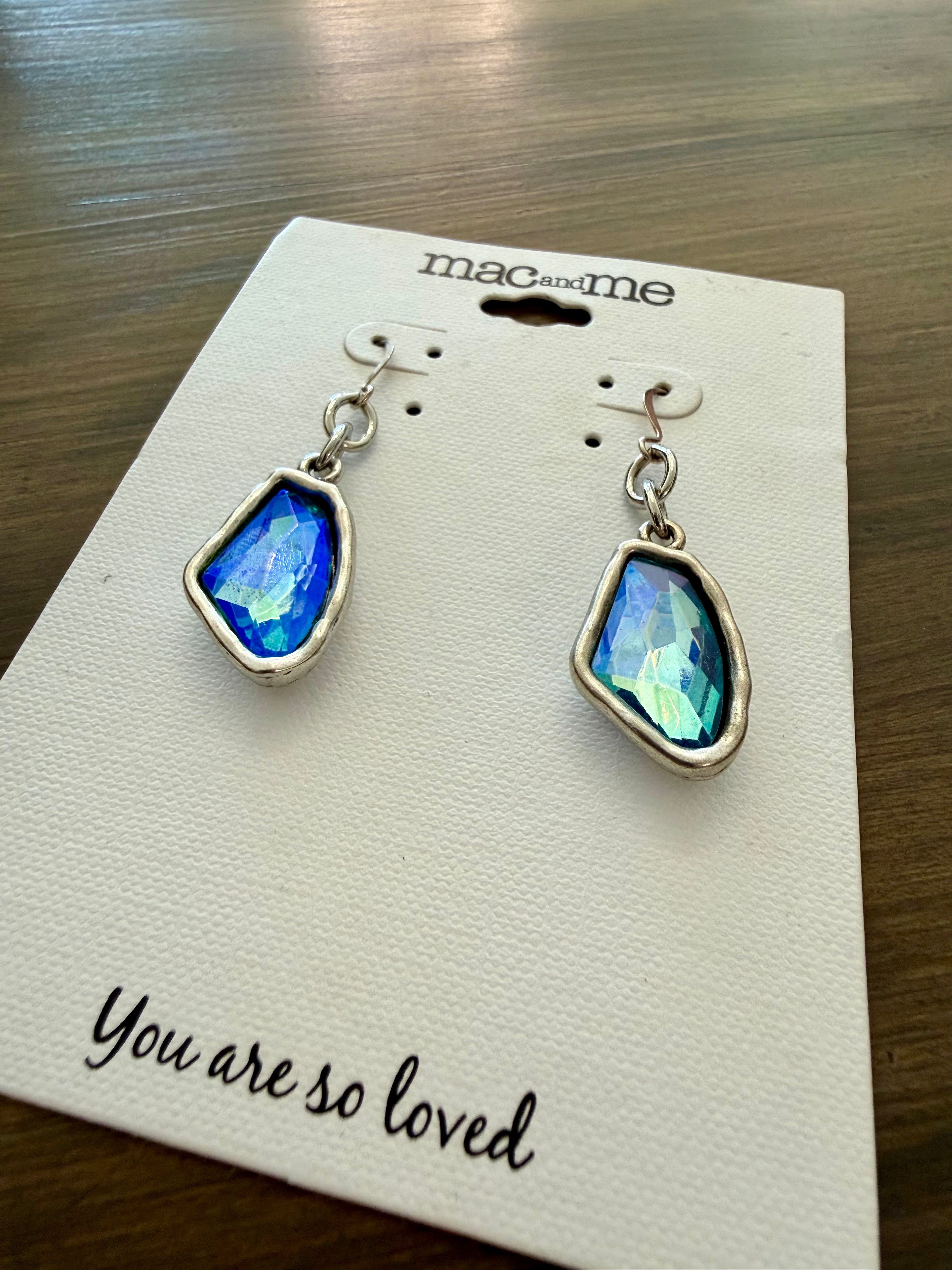 Pair of earrings on a 'mac and me' card with 'You are so loved' text on a wooden surface.