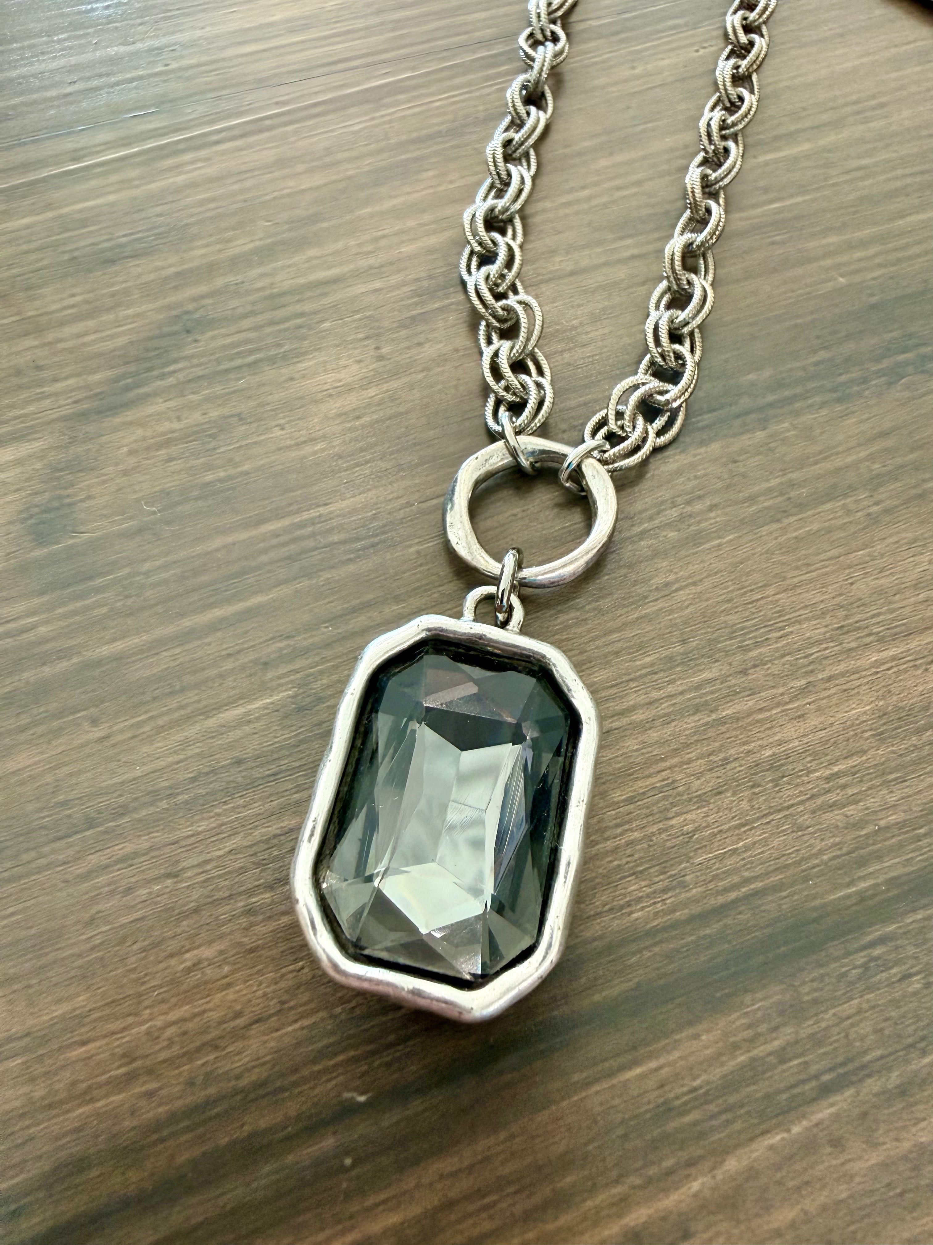 Necklace with a pendant featuring a dark green gemstone on a wooden surface