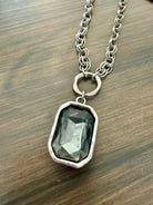 Necklace with a pendant featuring a dark green gemstone on a wooden surface