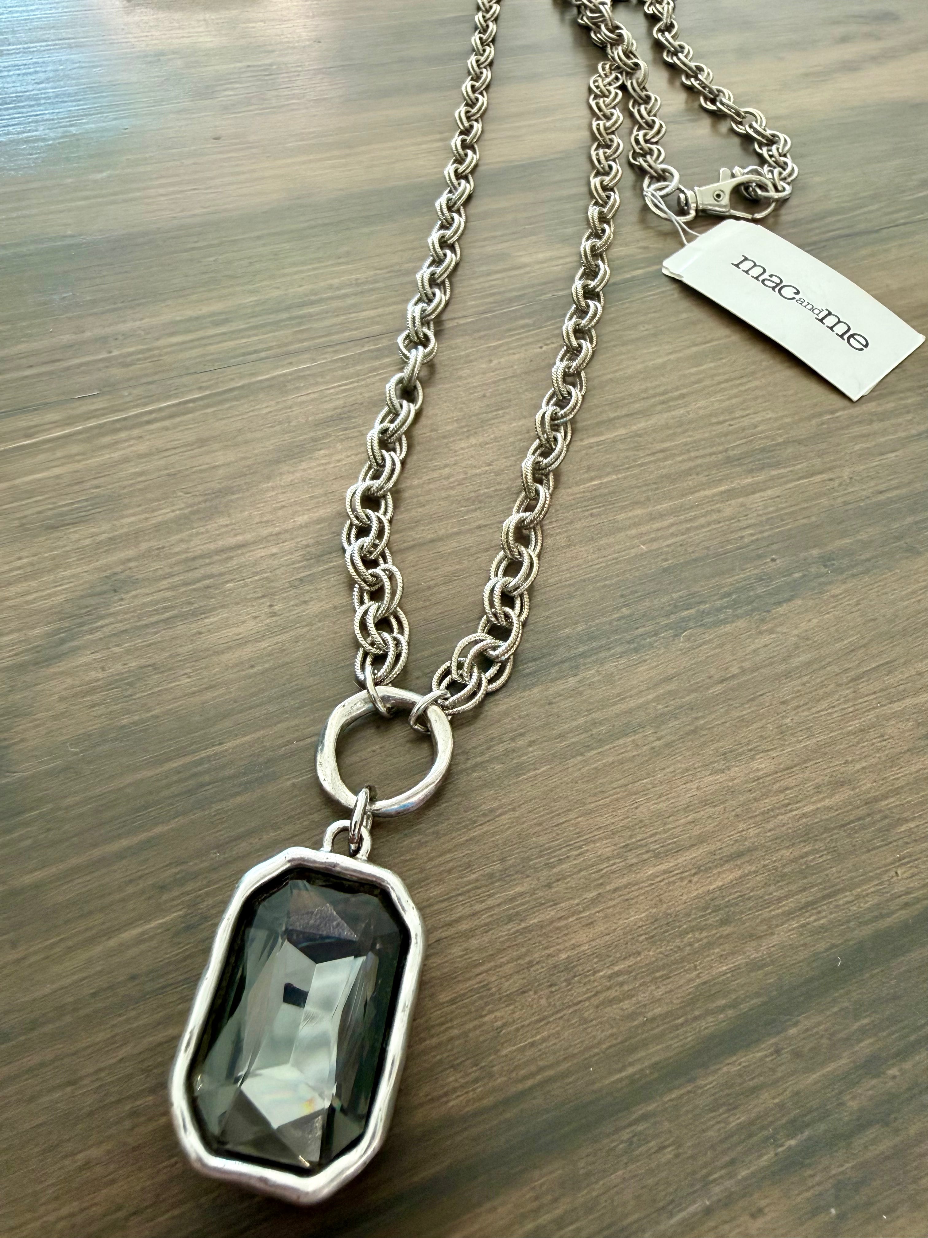 Necklace with a pendant on a wooden surface, featuring a visible brand tag.