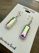 Pair of earrings on a 'mac and me' branded card with a message on a wooden surface.