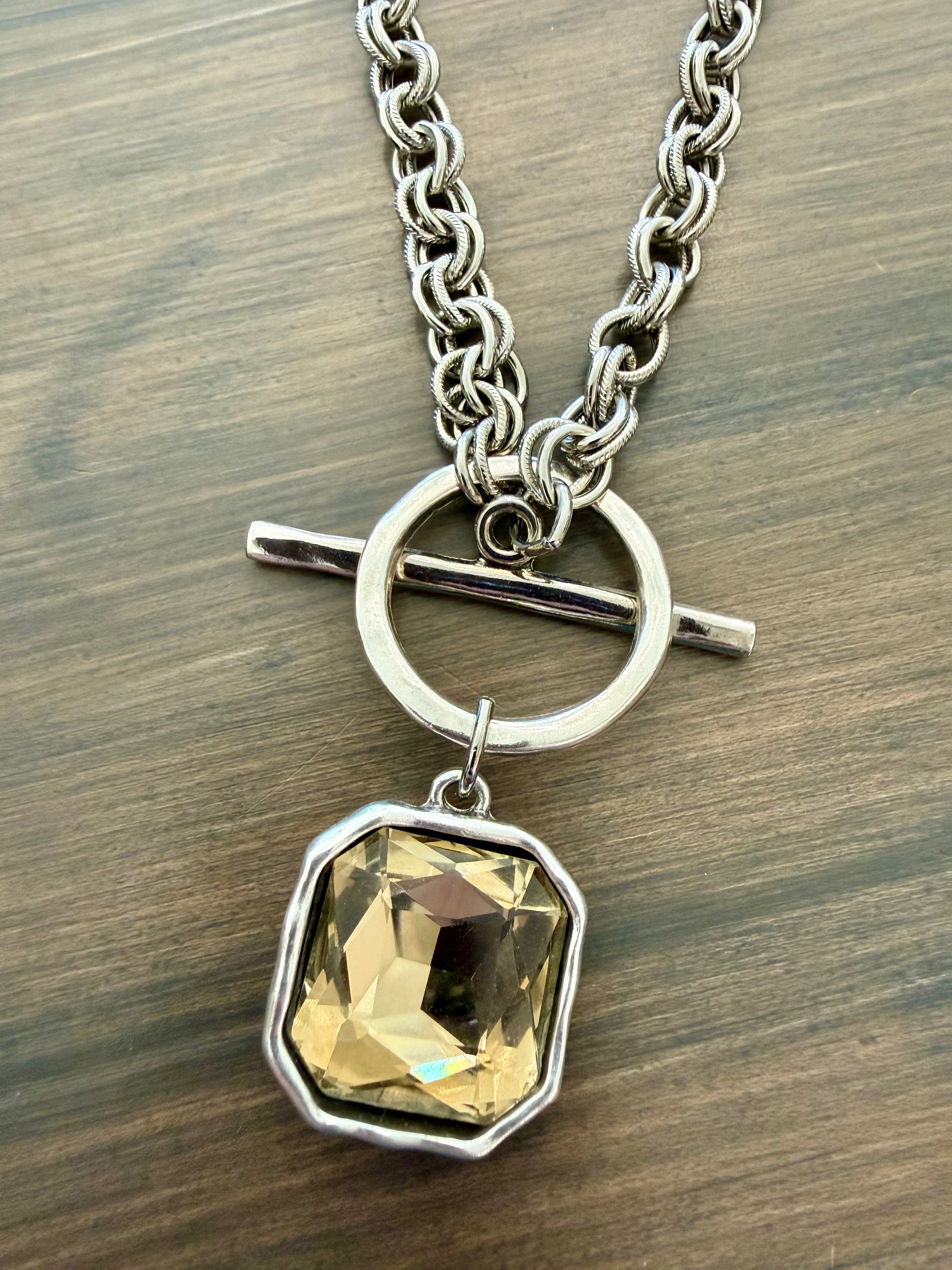 Necklace with a yellow gemstone pendant on a wooden surface
