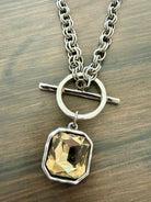 Necklace with a yellow gemstone pendant on a wooden surface