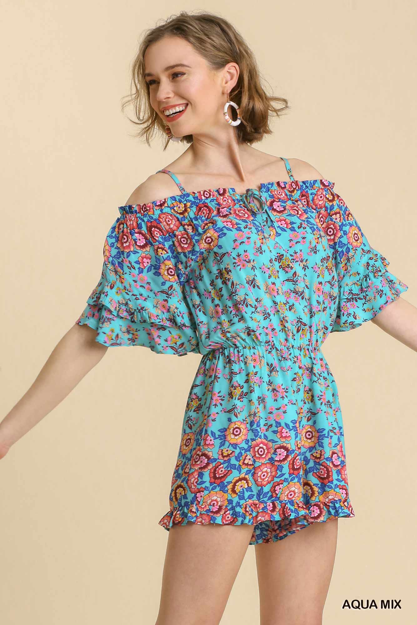 Woman wearing a colorful floral off-shoulder romper on a beige background