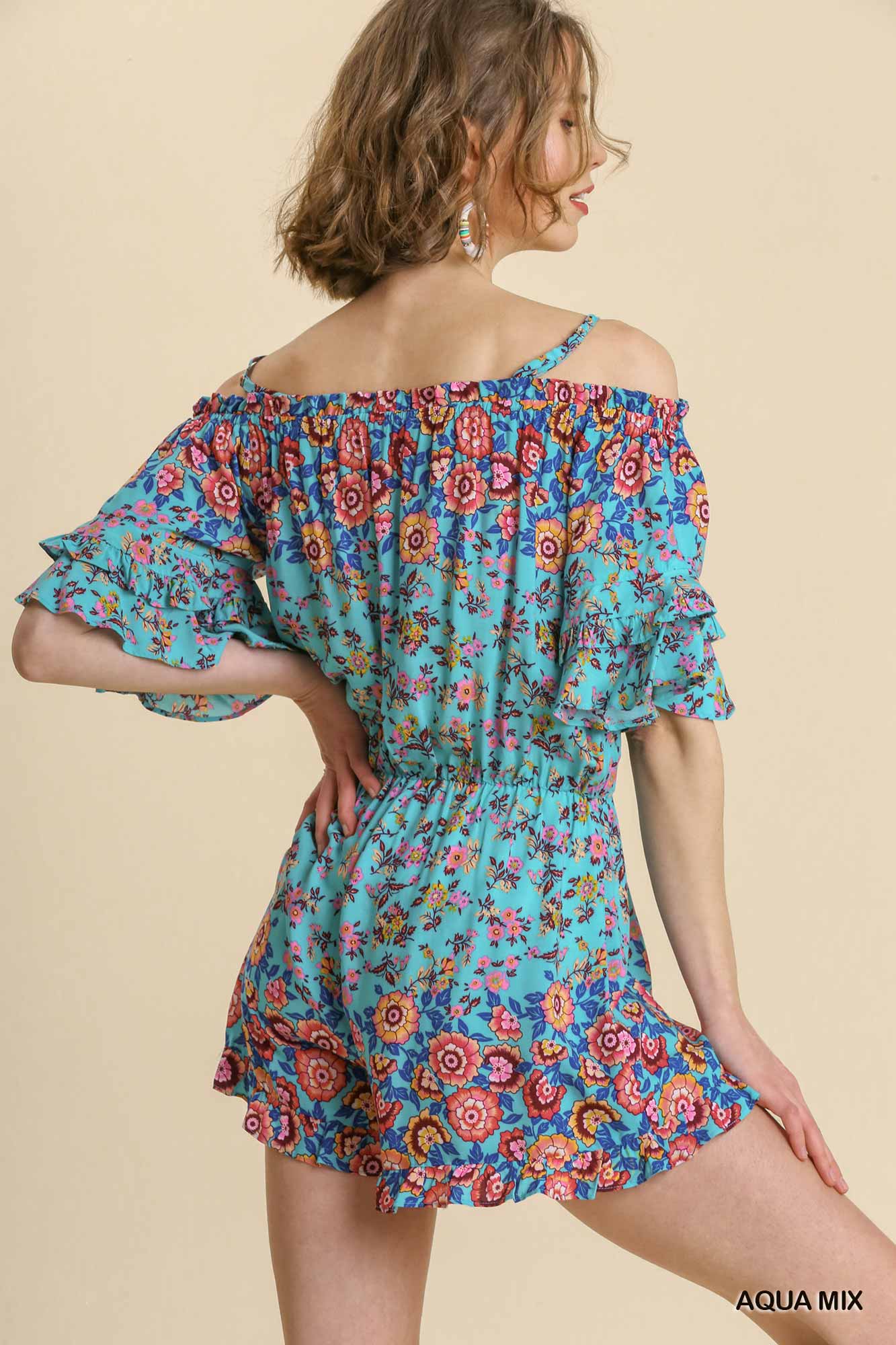 Woman wearing a colorful floral off-shoulder romper on a beige background