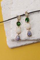 Earrings with multicolored gemstones on a textured stone surface