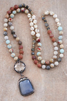 Two beaded necklaces with stone pendants on a textured surface