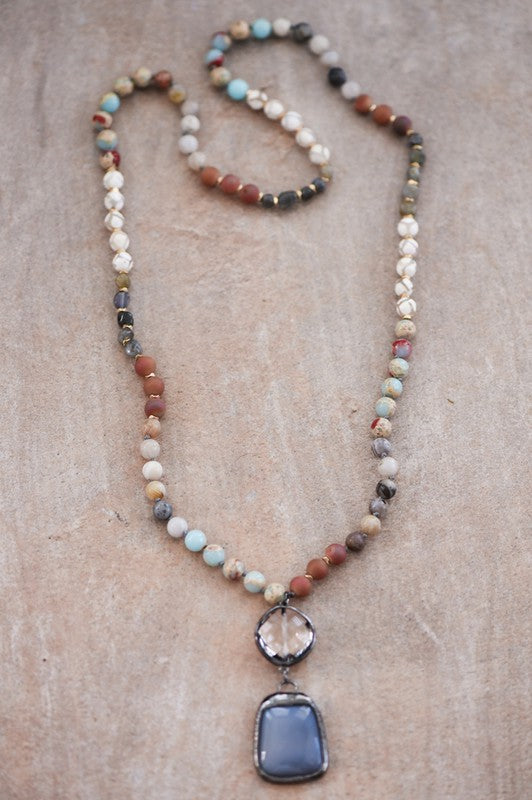 Necklace with multicolored beads and a large pendant on a textured surface