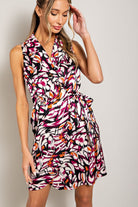 Woman wearing a colorful patterned dress against a plain background