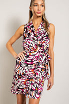 Woman wearing a colorful patterned dress against a plain background