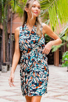 Woman wearing a colorful patterned dress in an outdoor setting with palm trees.