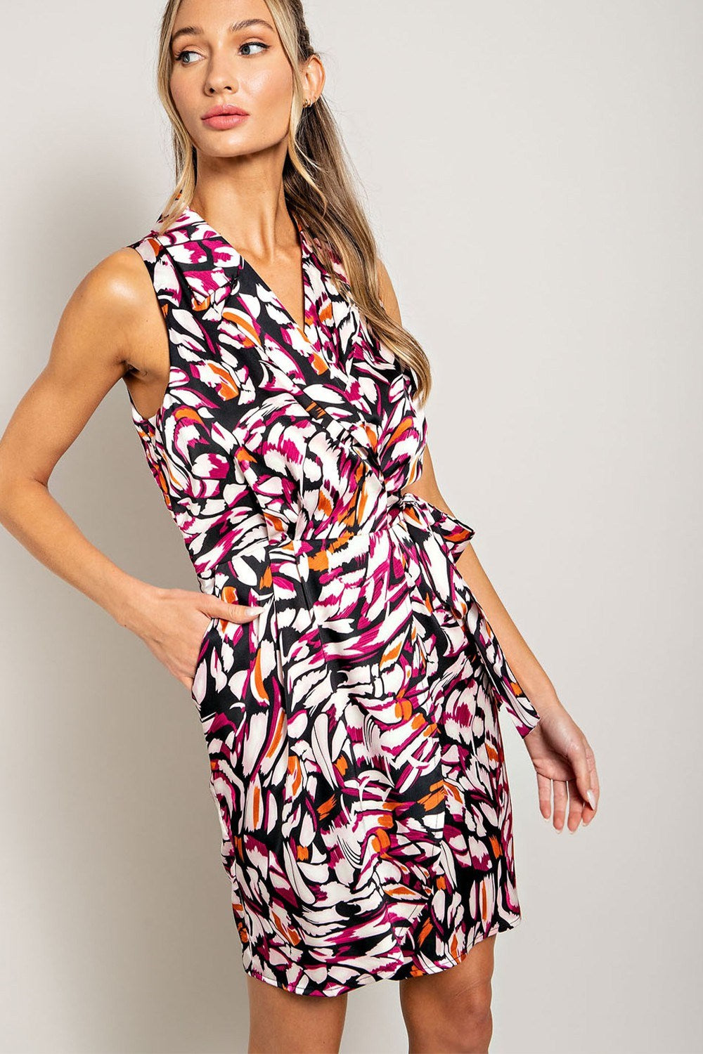 Woman wearing a colorful patterned dress against a plain background