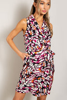 Woman wearing a colorful patterned dress against a plain background