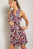 Woman wearing a colorful patterned dress against a plain background