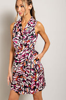 Woman wearing a colorful patterned dress against a plain background