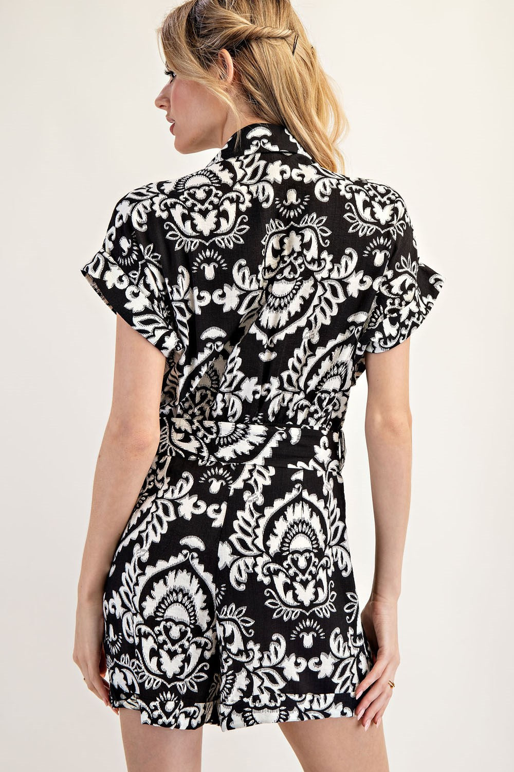 A woman wearing a black and white patterned dress on a plain background