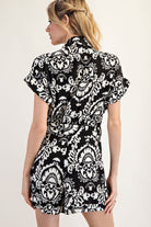 A woman wearing a black and white patterned dress on a plain background