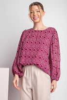 Woman wearing a pink patterned blouse against a plain background