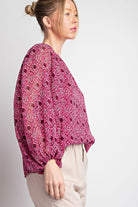 Woman wearing a pink patterned top on a white background