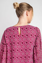 Pink patterned blouse worn by a person with a plain background