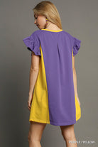 Woman wearing a purple and yellow dress against a gray background