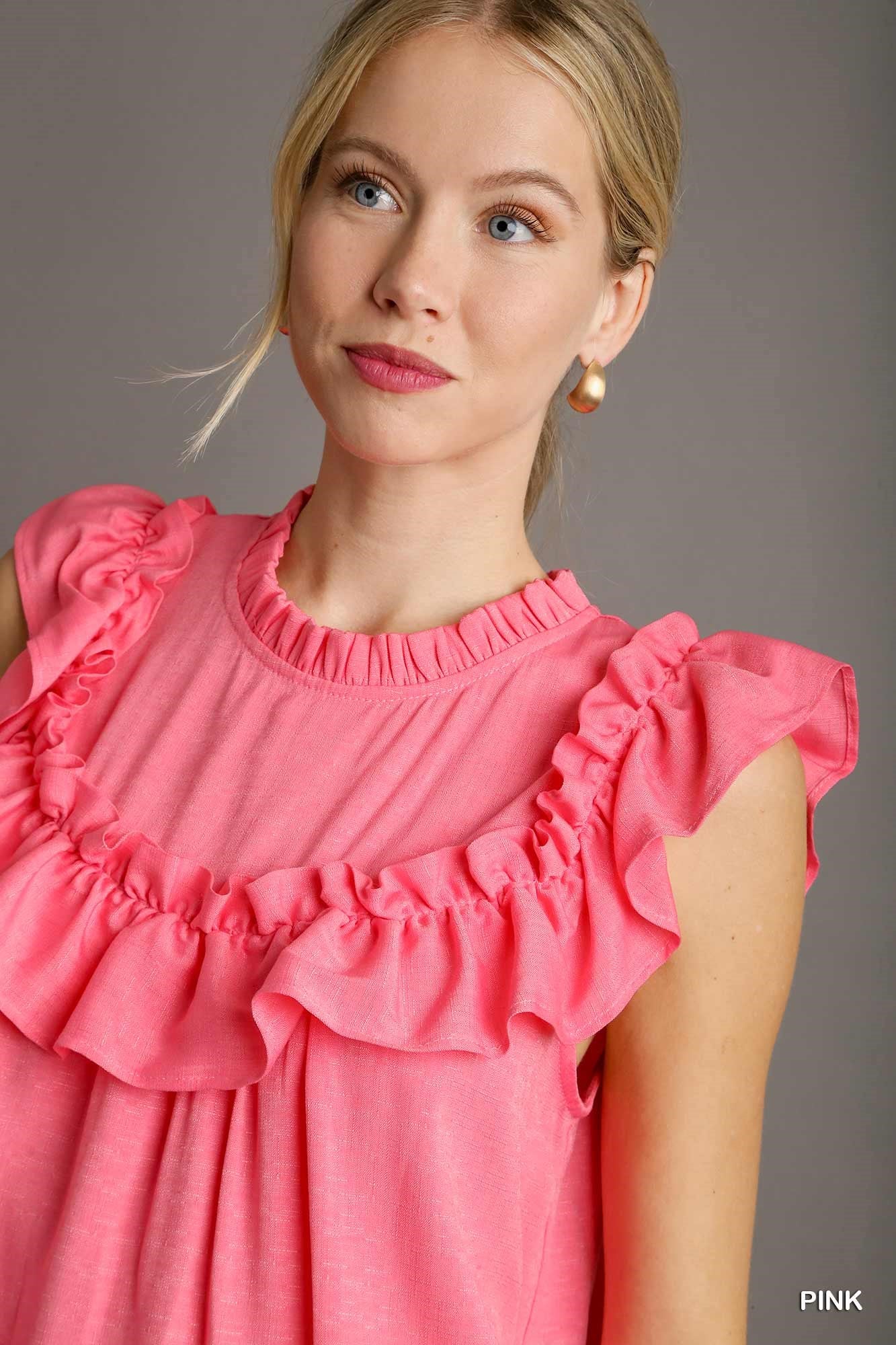 Woman wearing a pink dress with ruffled details against a gray background