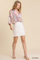 Woman wearing a striped blouse and white skirt on a beige background